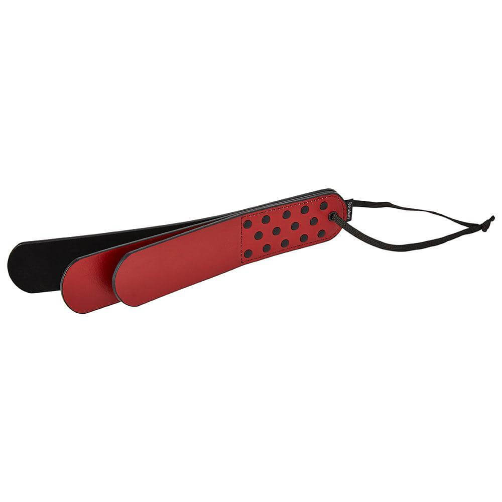 The Sportsheets Saffron Layer Paddle resting on its side, the three layers of the paddle spaced away from one another to showcase the triple layer slapper design. | Kinkly Shop
