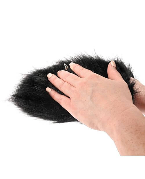 The Sportsheets Spiked Sensory Mitt is laying flat on a plain white background. They are using their other hand to pet the faux fur of the Mitt. The faux fur looks very soft and plushy. | Kinkly Shop