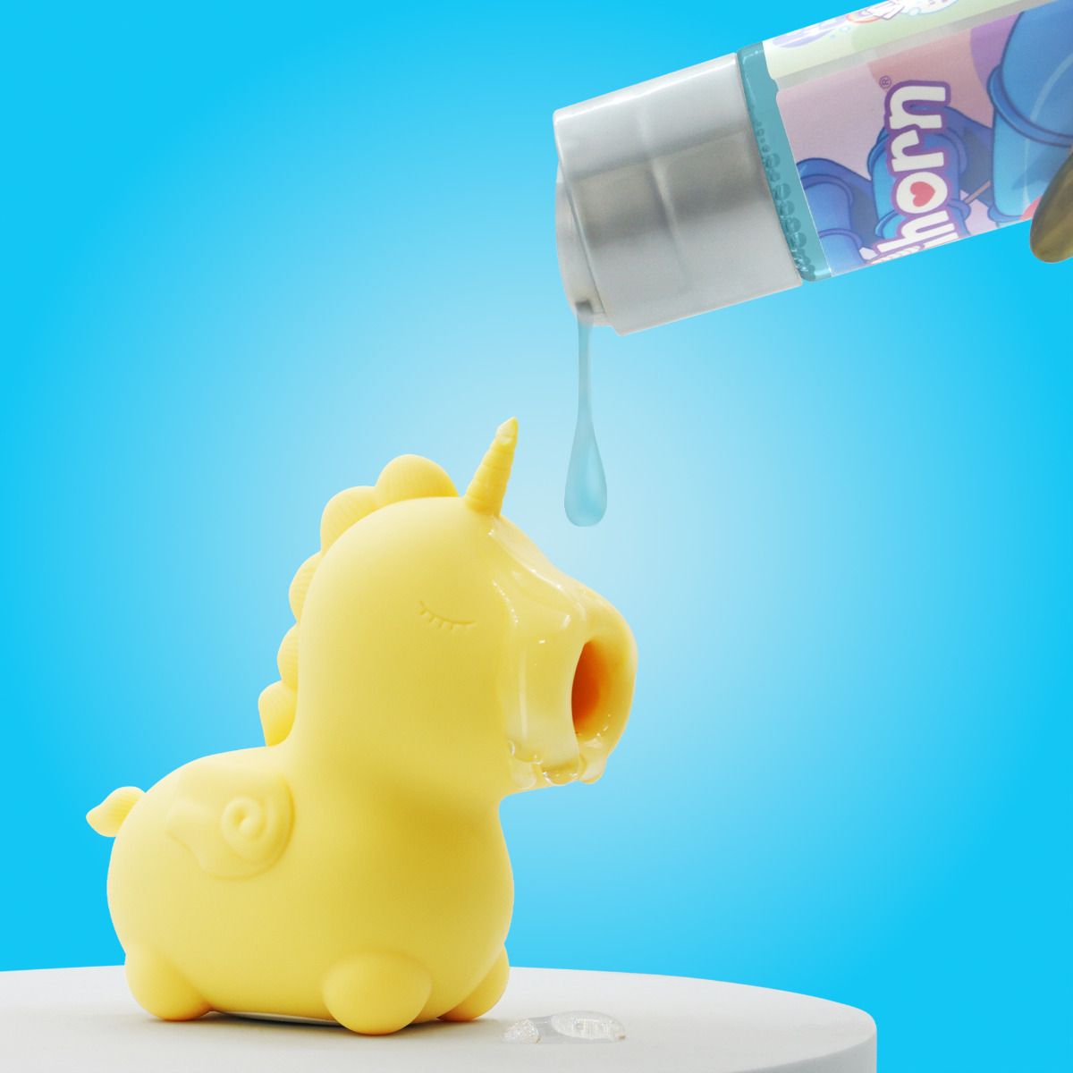 A person pours a dab of the Unihorn Lube - 4.4 oz onto the nozzle of the air suction toy. | Kinkly Shop