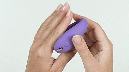 A person lays their palm out flat. They slide the We-Vibe Sync Go onto their palm, letting it "clamp" around the palm, showcasing the U-shaped design of the toy and how it would slide into two places at once. | Kinkly Shop