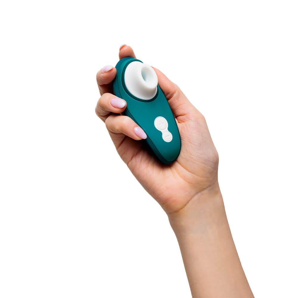 A hand holds the Womanizer Liberty 2. It's a short vibrator, fitting entirely into the palm of their hand with lots of room to spare around all sides. | Kinkly Shop