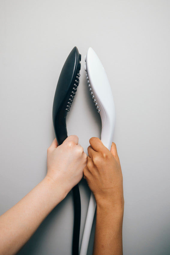 The Womanizer Wave in black and white held next to one another, showcasing the difference in the two colors. | Kinkly Shop