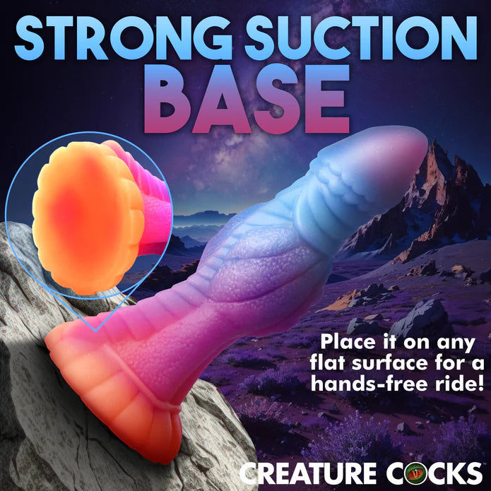 The Creature Cocks Galactic Cock shown stuck up on a cracked boulder. Text reads: Strong suction base. Place it on any flat surface for a hands-free ride. | Kinkly Shop