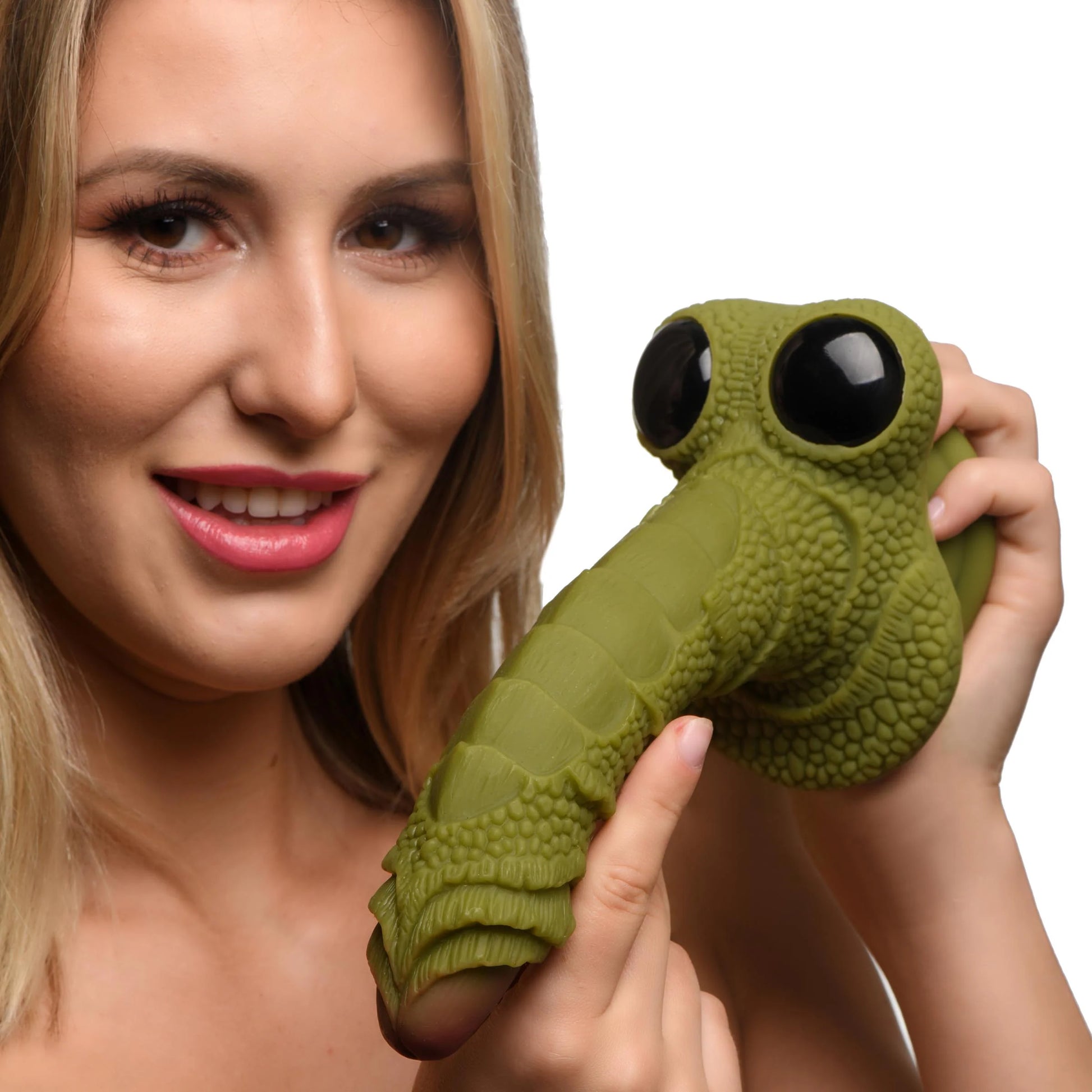 A person holds the Creature Cocks Swamp Monster up to the camera. The dildo is an average-sized dildo but it looks like a bug face with two glass "eyes" at the base. | Kinkly Shop