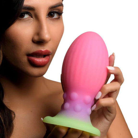 A person holds the Creature Cocks XL Xeno Egg. It's particularly big, and it looks almost slightly smaller than the model's face from this angle. | Kinkly Shop
