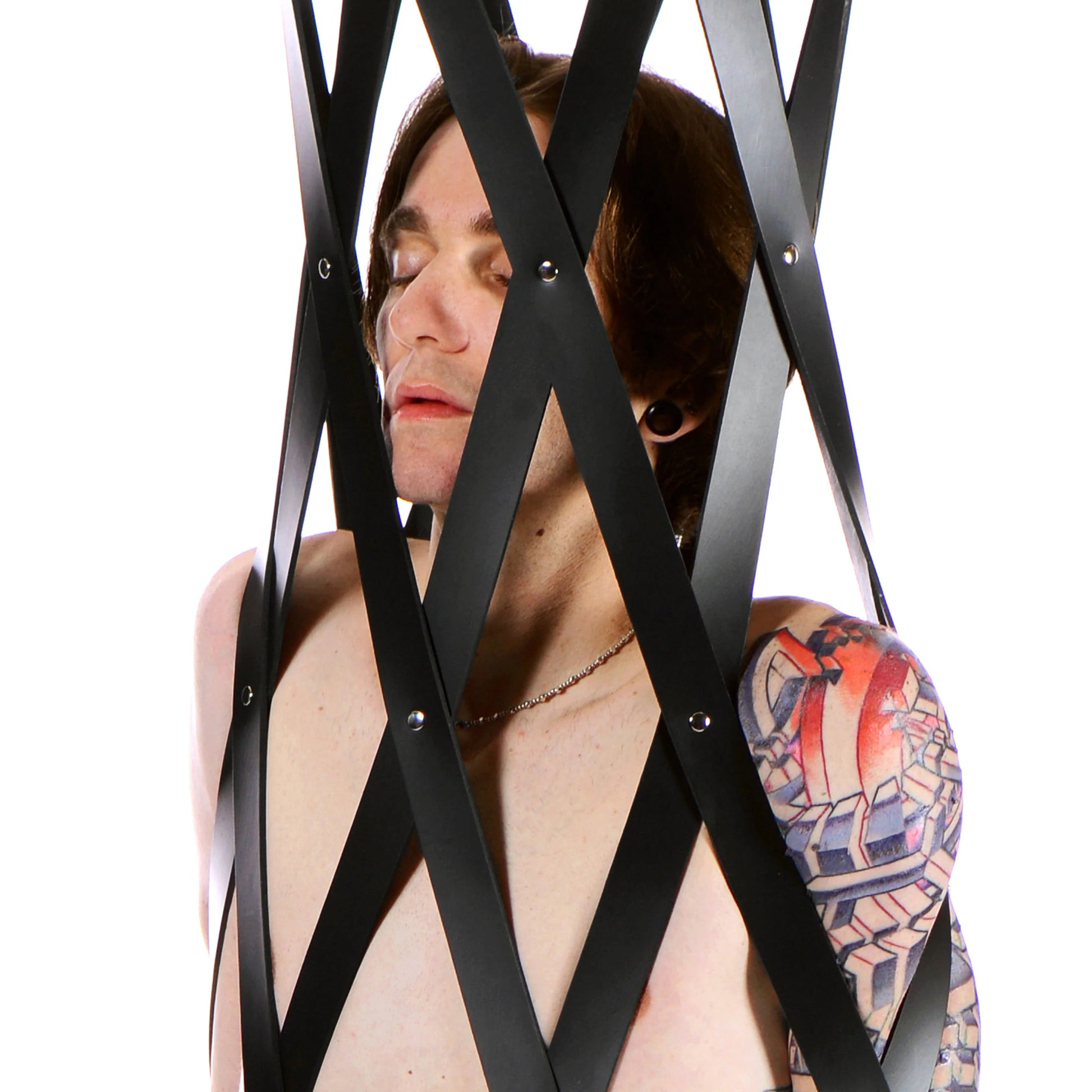 A close up on a person inside of the Hanging Rubber Strap Cage. This shows how tightly the rubber straps are securing them into the cage, holding them in place. | Kinkly Shop