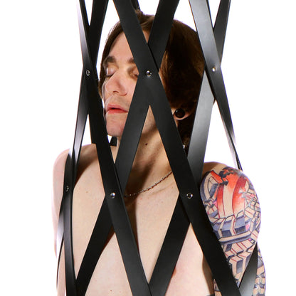 A close up on a person inside of the Hanging Rubber Strap Cage. This shows how tightly the rubber straps are securing them into the cage, holding them in place. | Kinkly Shop