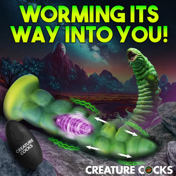 Cross-section of the Creature Cocks Squirmer Vibrating Thruster with Remote Control showcases the vibrating motor in the middle of the shaft with a thrusting tip. A remote is shown in the foreground, and a monster worm creature is shown in the background. | Kinkly Shop