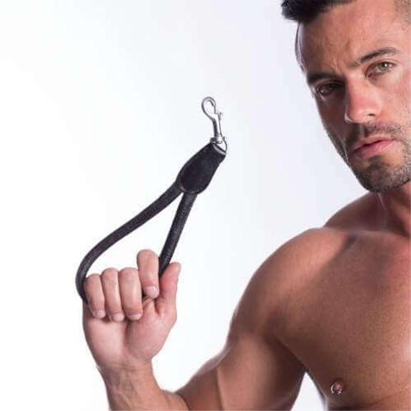 A person stares into the camera as they hold up the 665 Short Leash in front of a white background. The 665 Short Leash is extremely rigid and sturdy, and despite being held with the clip in the air, the 665 Short Leash still maintains its loop-like appearance. It does not bend. | Kinkly Shop