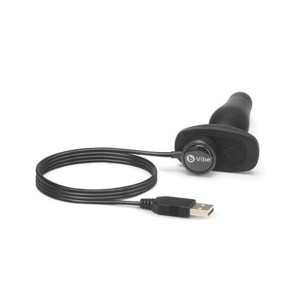 Close up of the base of the b-Vibe Remote Novice Plug with the magnetic charging cable placed on the magnetic charging port at the base. | Kinkly Shop