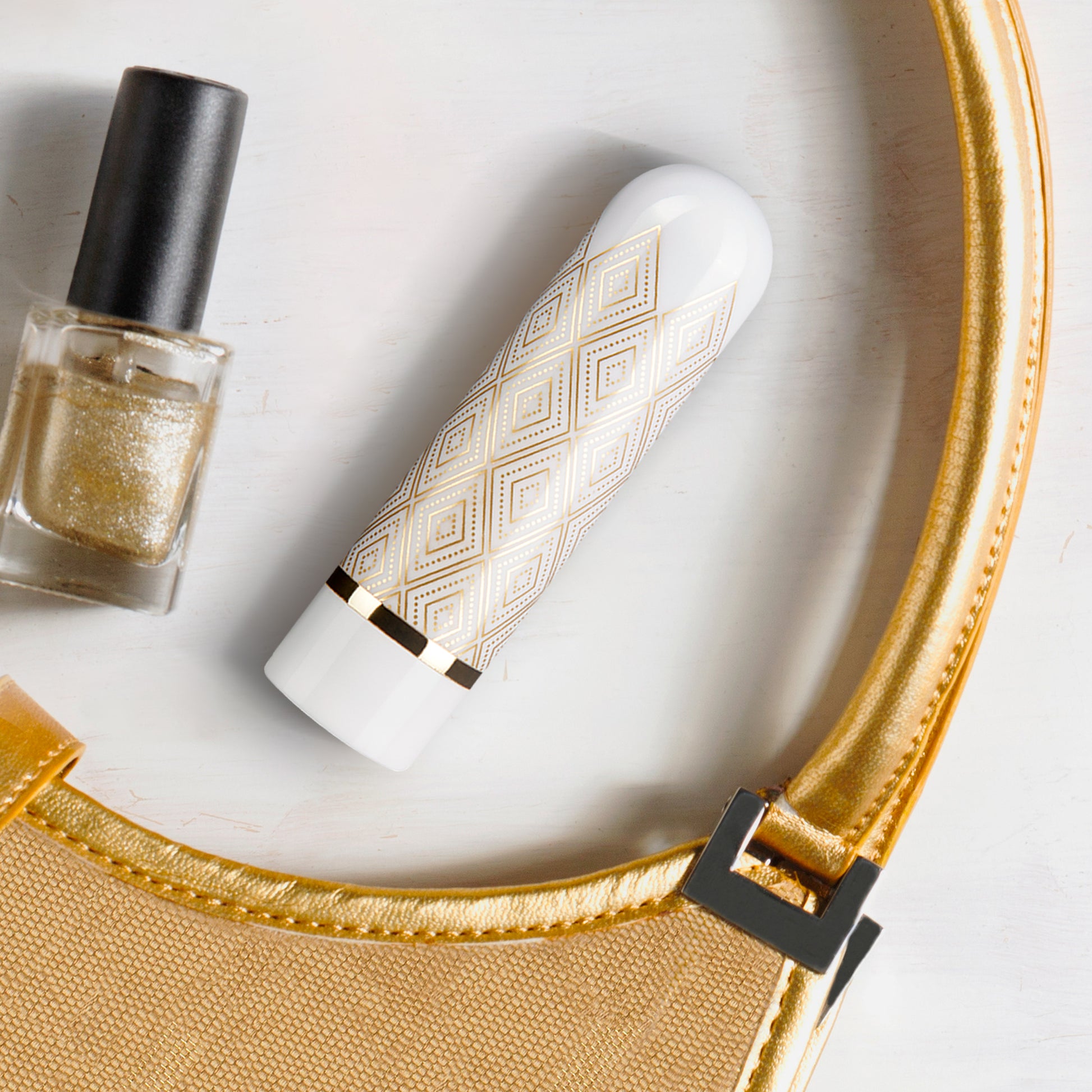 Blush Glitzy Deco Gold sitting on a table with nail polish and a purse for decoration | Kinkly Shop