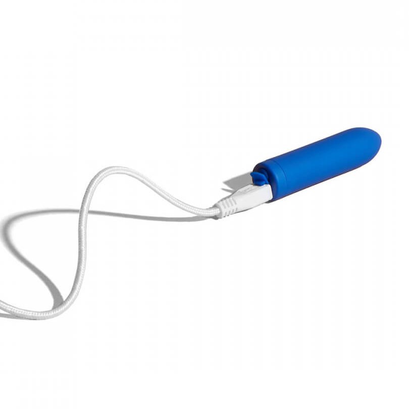 The charging cable plugged into the Dame Zee micro bullet vibrator. The image shows the charging port's cover opened up to make room for the cable to slide into the vibrator. | Kinkly Shop