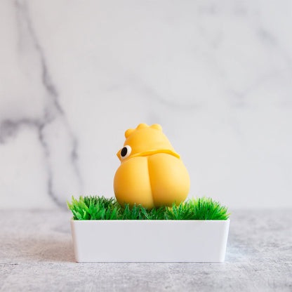 The Emojibator Chickie rests in a small bed of "grass" with its butt facing towards the camera. It has a bubble butt with a clear line and cheek curves to boot. | Kinkly Shop