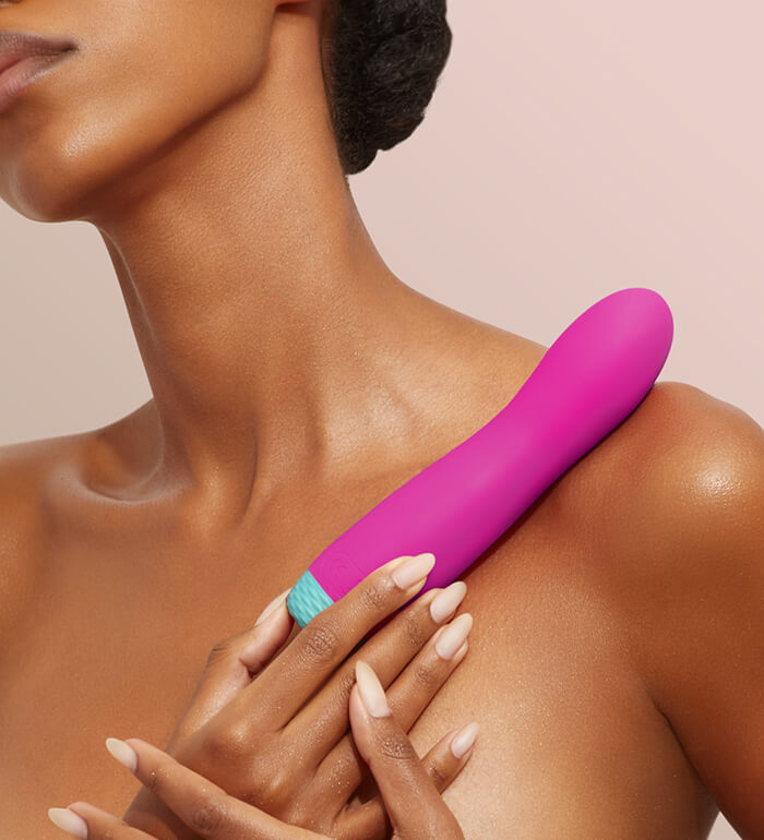 A person holds the FemmeFunn Rora Rotating Bullet up against their shoulder. | Kinkly Shop