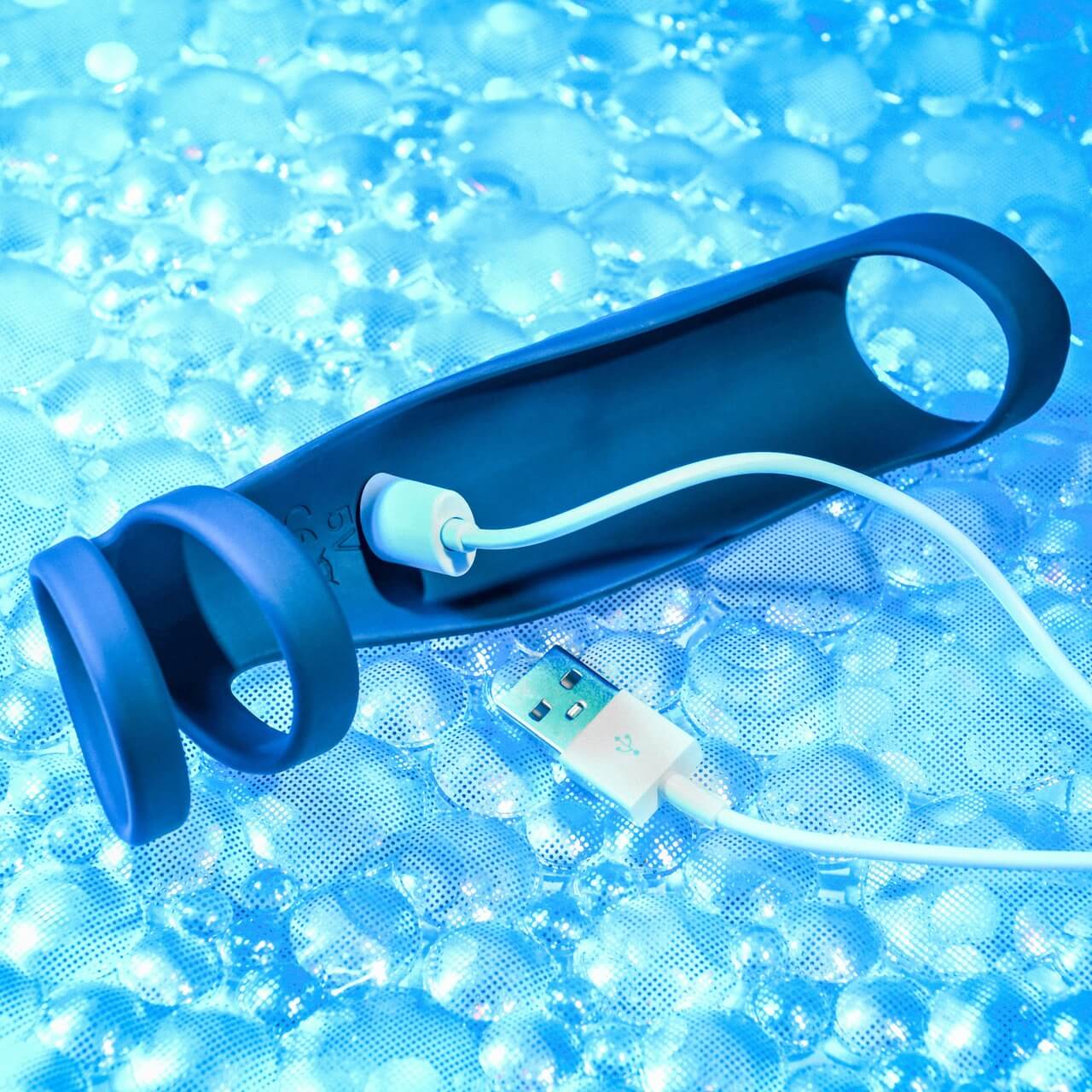 The magnetic charging cable is connected to the charging port of the Gender X Rocketeer. The port is located within the underside/chamber of the Gender X Rocketeer that would usually rest against the top of the penis while the Rocketeer is being worn. | Kinkly Shop