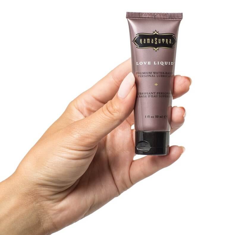 A hand holds the Love Liquid water-based lube. It looks like a travel-sized container of lube at a length that's longer than a finger. It's a squeeze bottle. | Kinkly Shop