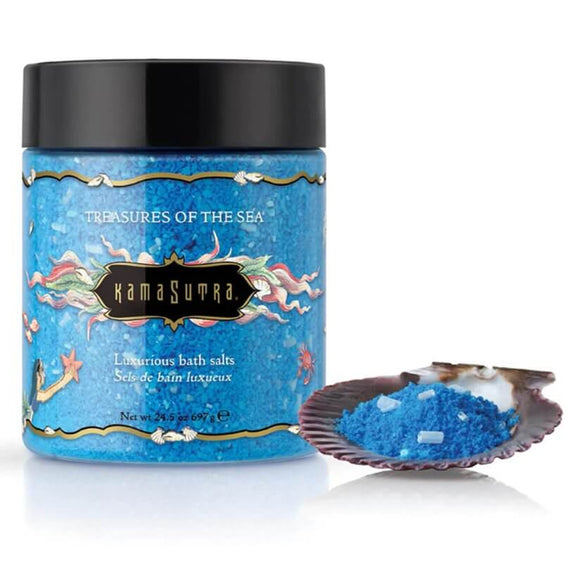 Kama Sutra Treasures of the Sea Bath Salts in front of a white background. A small brown shell is shown in the foreground that is holding some of the blue balt salts, ready to pour. | Kinkly Shop