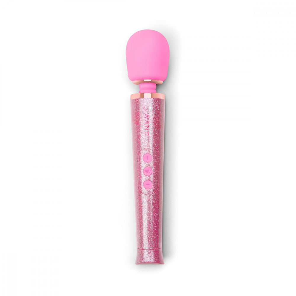 The Pink Le Wand All That Glimmers Wand Massager laying out on a flat surface. The wand's handle is extremely sparkly and glittery. The head of the petite wand massager is in a color-matching silicone. The three buttons on the handle also match the silicone look of the head. | Kinkly Shop