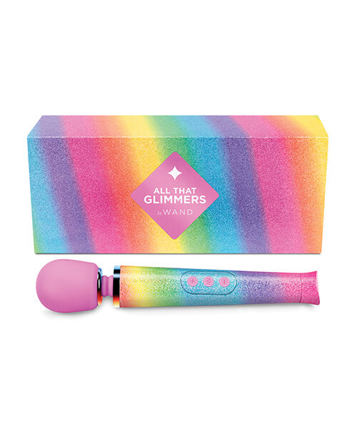 The Le Wand Rainbow Ombre Petite Wand Massager rests out against a white background in front of the packaging for the toy. The packaging is bright and rainbow colored, and it matches the colors of the wand. The box is large and rectangular and would be easy to gift wrap. | Kinkly Shop