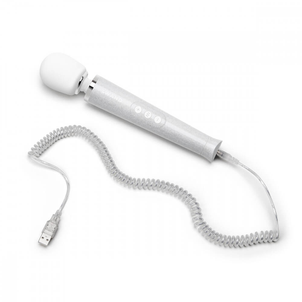 The Le Wand All that Glimmers Wand Massager laying out on a flat surface. Its color-matching charging cord is attached at the base of the wand. The cord includes spirals in a 90's style as well as a glitter coating that matches the wand massager. | Kinkly Shop