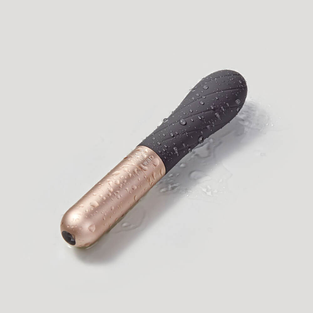 The Love Not War Grá sits out on a grey background, covered in droplets of water. This is to showcase that the Love Not War Grá is waterproof - and it just looks pretty. | Kinkly Shop