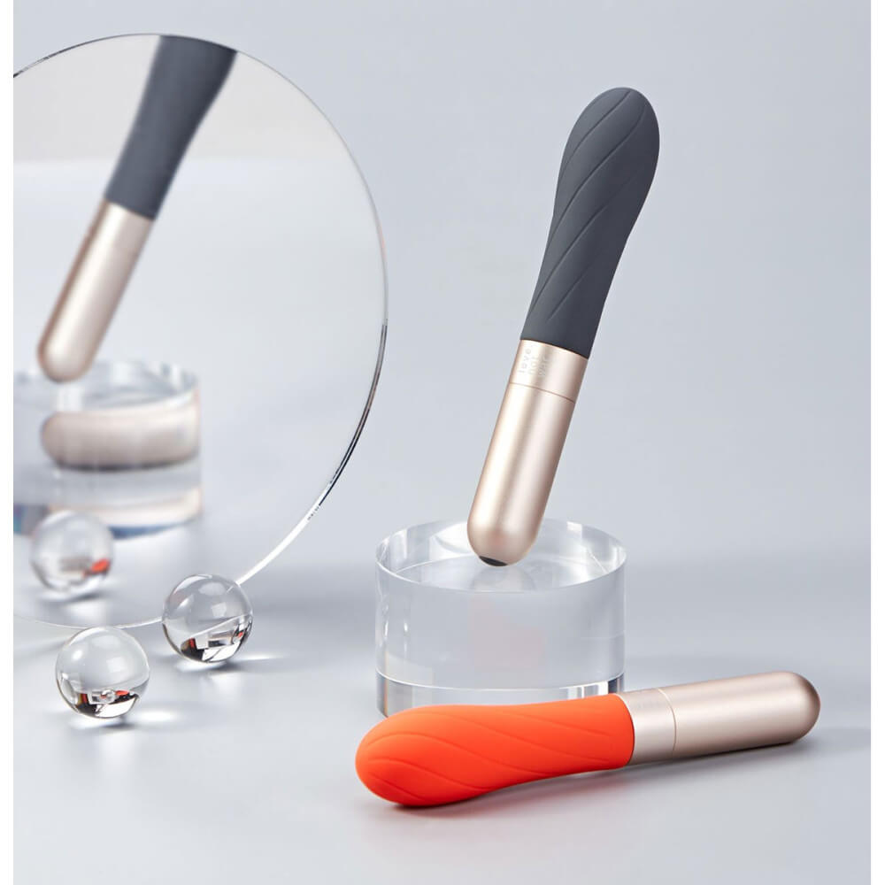 The Love Not War Grá in Orange and in Grey sit out against a grey background surrounded by geometric shapes like a mirror and glass balls. This showcases the differences between the vibes in color. | Kinkly Shop