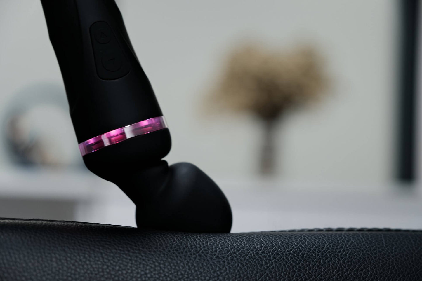 The Lovense Domi 2 is pressed up against a couch cushion. The image shows that the head clearly bends under the pressure with ease. | Kinkly Shop