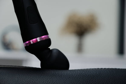 The Lovense Domi 2 is pressed up against a couch cushion. The image shows that the head clearly bends under the pressure with ease. | Kinkly Shop