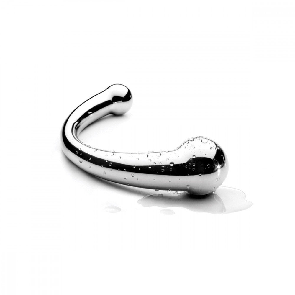 The Njoy Pure Wand lays out flat on a white surface. The surface of the dildo is covered in small water droplets with a puddle underneath the dildo. They shine against the dildo's surface and showcase its waterproof capabilities. | Kinkly Shop