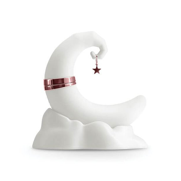 The NS Novelties Firefly Dream Glow up against a white background in daylight. It's extremely white, and it almost blends into the background. The toy is crescent moon shaped with a star charm hanging off the tip. It sits upright without the help of a hand because it's resting in its charging base that looks like a pillowy cloud. | Kinkly Shop