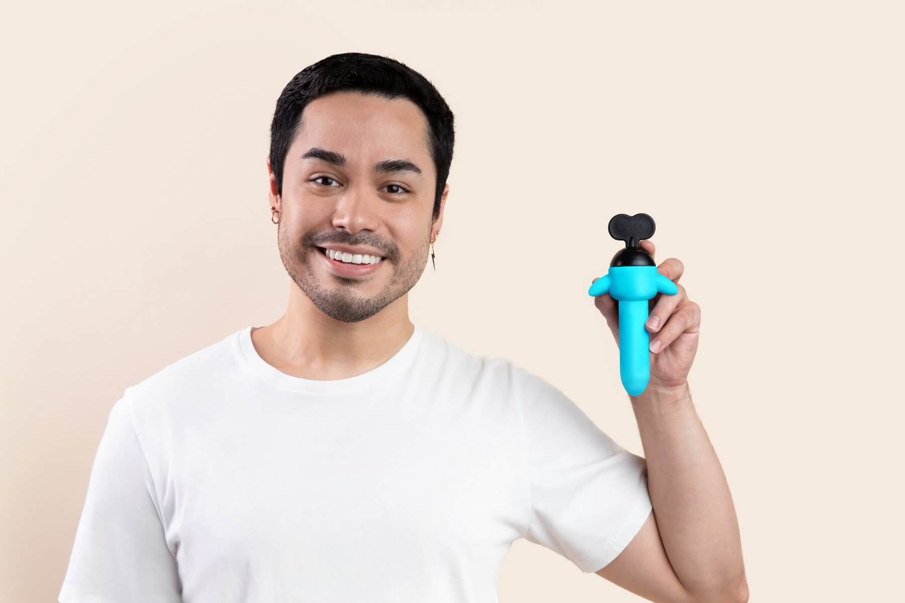 A person smiling is holding up an Odile Absolute while looking at the camera. This showcases the Absolute's length which is about as long, from twist key to tip, as the person's tip of their finger to the base of their palm. | Kinkly Shop