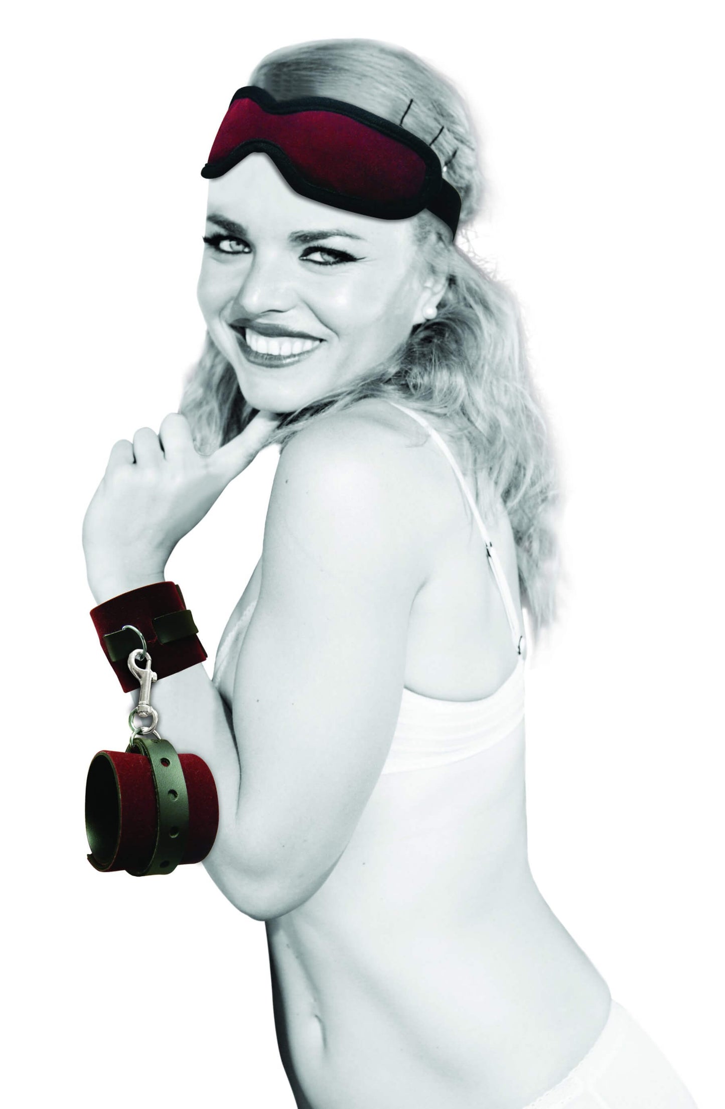 A happy, smiling person looks at the camera. The blindfold from the Sportsheets Enchanted Kit is resting on top of their head. One of the wrist restraints from the Sportsheets Enchanted Kit is on their wrist while the second restraint dangles from the one that's fastened on their wrist. | Kinkly Shop