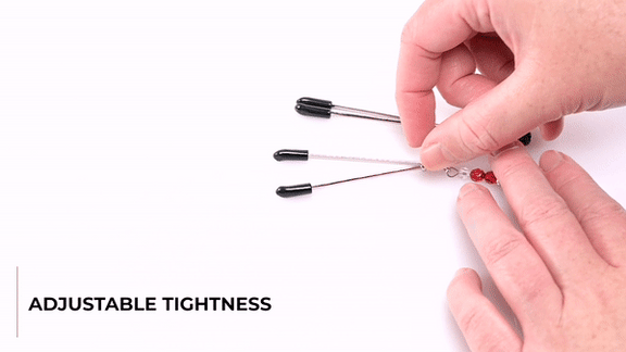 GIF showing someone handling the Sportsheets Ruby Black Nipple Clamps. The GIF shows the Adjustable Tightness through the rings on the shafts of the nipple clamps. The text says "Rings Slide Down: For Snug-As-You-Like Sensations". | Kinkly Shop