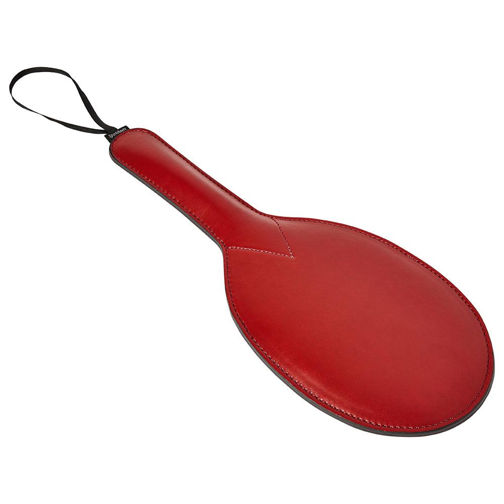Sportsheets Saffron Ping Pong Paddle lays on a flat, white surface. This angle showcases the thickened diameter of the handle for easier handling as well as the simple loop at the base of the handle for more secure and easier handling. | Kinkly Shop