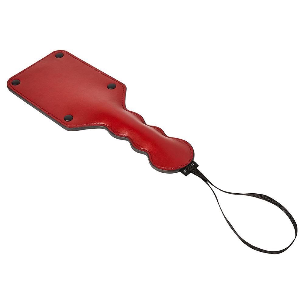 Sportsheets Saffron Square paddle laying down on a flat, white surface. This angle showcases the raised thickness of the handle for easier gripping as well as the long, spacious wrist loop for easier and more secure handling. | Kinkly Shop
