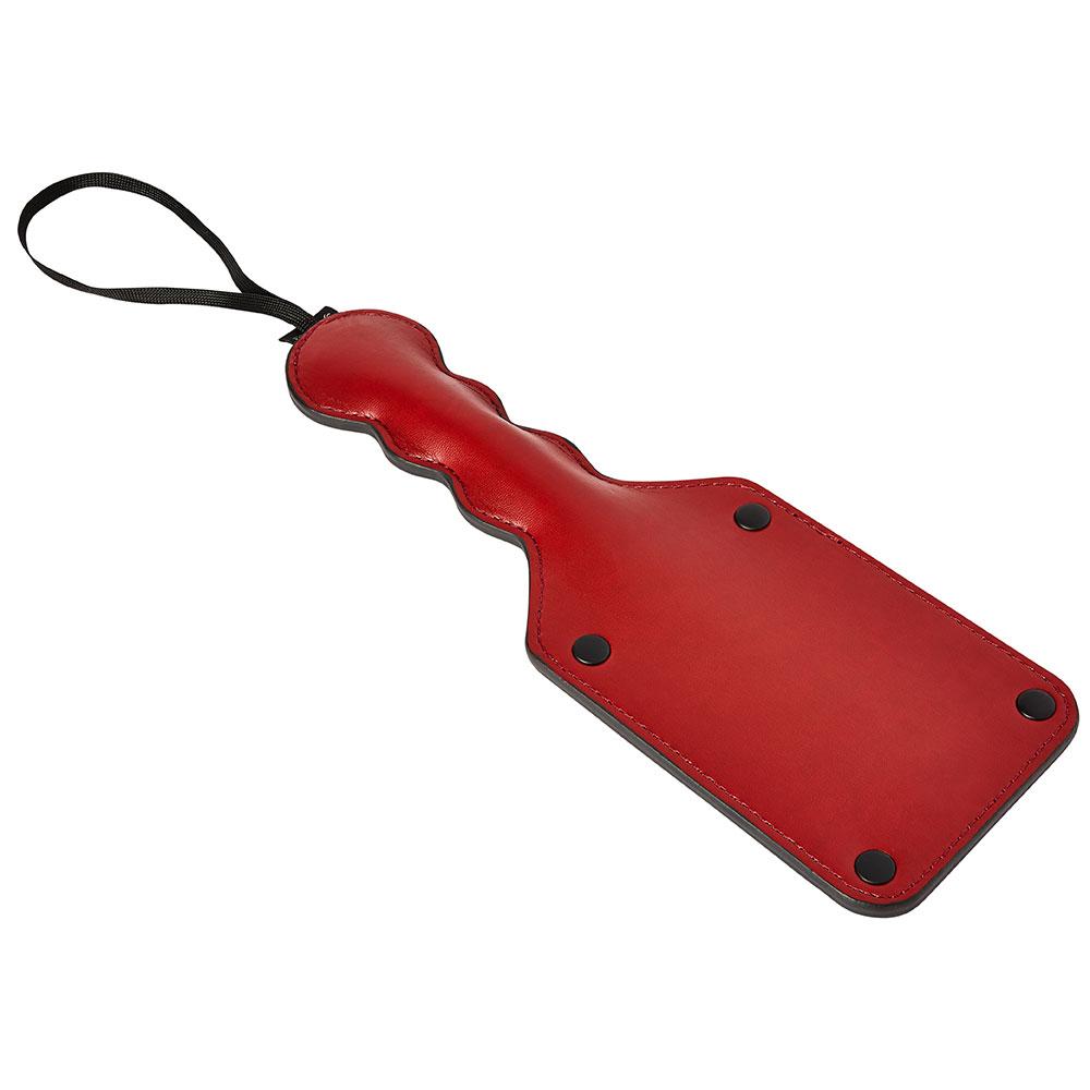 Sportsheets Saffron Square paddle laying down on a flat, white surface. This angle showcases the raised thickness of the handle for easier gripping as well as the long, spacious wrist loop for easier and more secure handling. | Kinkly Shop