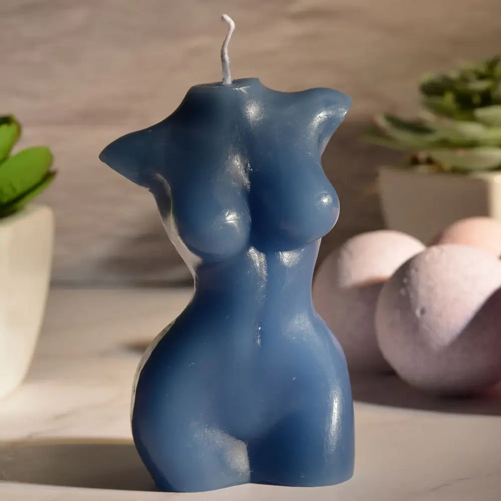 The Sportsheets Torso 3 Wax Play Candle sitting out on a marbled countertop with harsh, afternoon sun lighting that leaves parts of the calendar in dark shadows. | Kinkly Shop