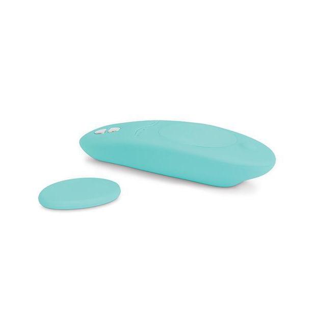 We-Vibe Moxie+ Panty Vibe lays out on a white background. The magnet is sitting next to the vibrator to show how it comes off to allow it to fasten the vibrator to any spot on underwear. | Kinkly Shop