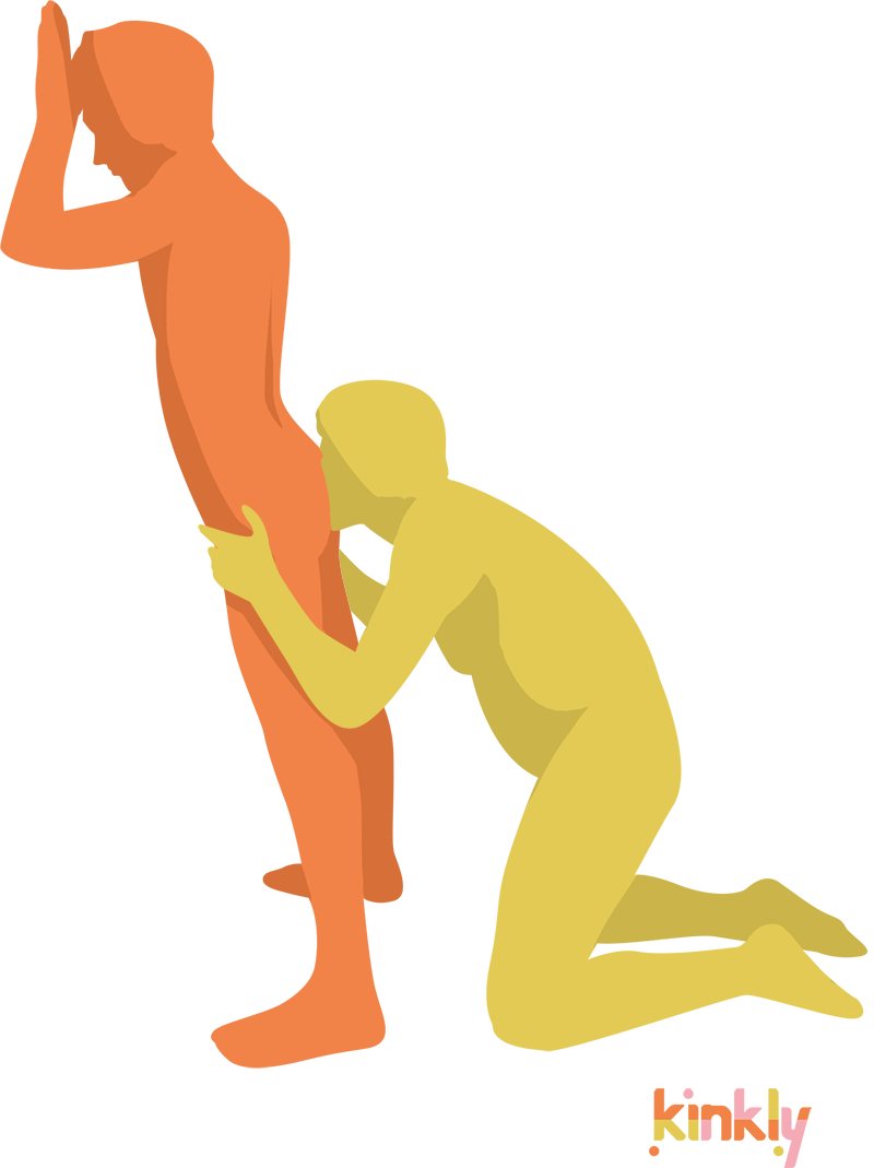 The receiving partner is facing a wall, bracing themselves on the wall. The giving partner kneels to place their face between the receiver's butt cheeks.
