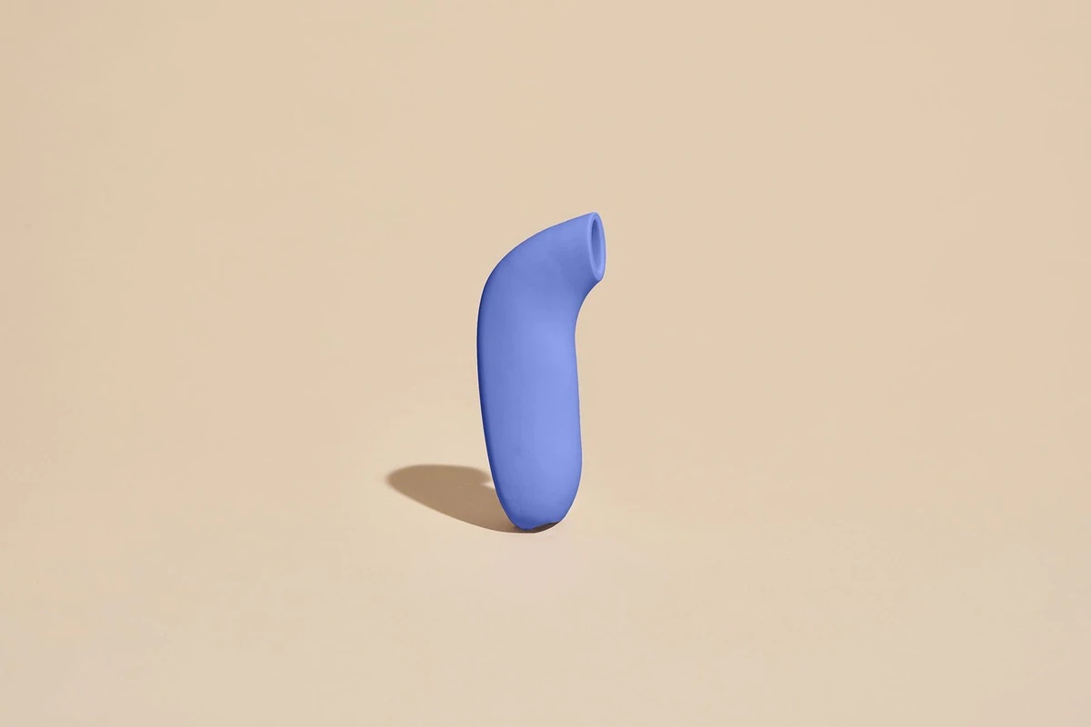 The Dame Products Aer: A periwinkle suction vibrator composed of a long thin cylindrical handle and an upward-slanted circular suction cup at the head for clitoral stimulation.