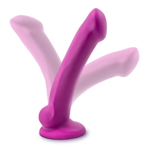 The Blush Real Nude Ergo Mini: A neon pink dildo with a suction cup base. A shadow of the dildo is pictured in front of and behind it, indicating its ability to move forwards and backwards while staying in place.