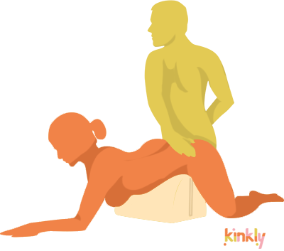 Double Mount Penetration Position: The receptive partner lays face-down with a piece of sex furniture underneath their hips to prop them up. The insertive partner kneels behind them for penetration.