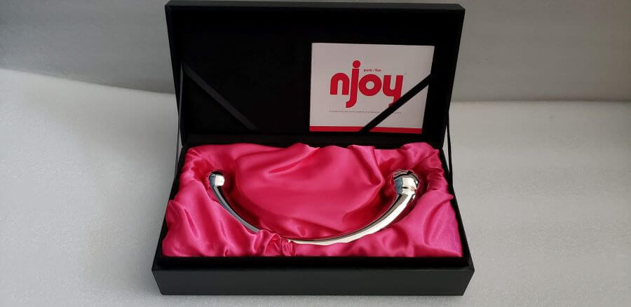 The Njoy Pure Wand displayed in an open box on a bed of pink velvet.